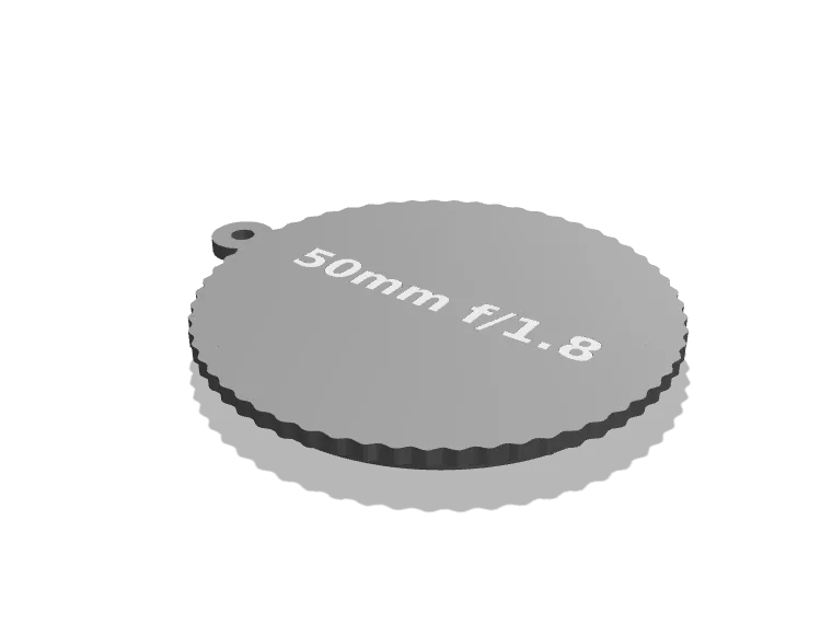 Black 3D printed lens cap with 50mm f/1.8 inlaid in white and a leash eyelet